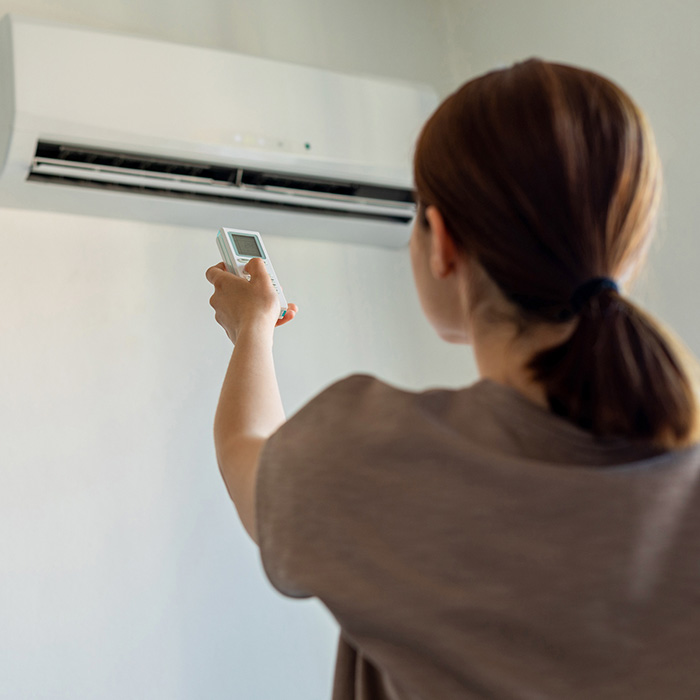 Woman turning on air conditioner with remote